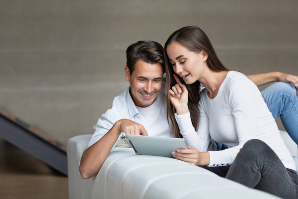 Happy couple using a tablet computer in iving room, choose services on the Internet, online shopping. - Φωτογραφία, εικόνα