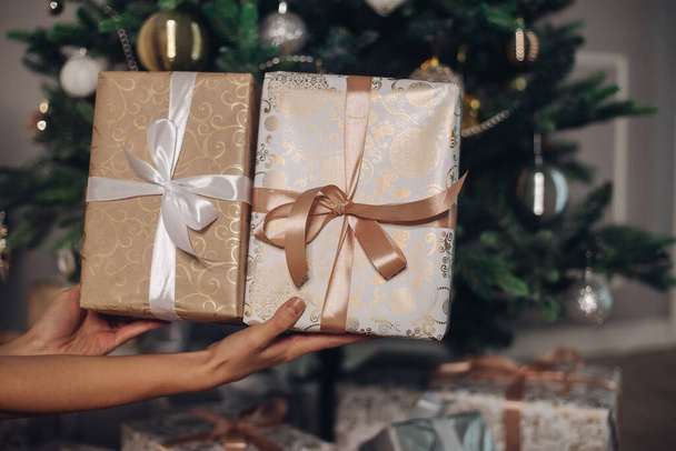 Причудливые подарки с лентами рядом с прекрасной елкой - Фото, изображение