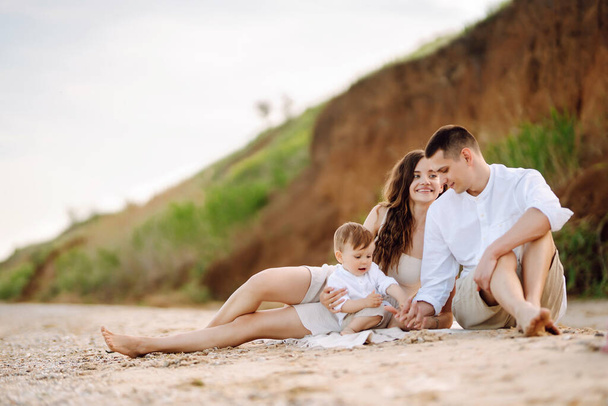 Young family on the beach. People are having fun on summer vacation. Father, mother and child against the background of the blue sea and sky. Travel, active lifestyle, vacation, rest concept. - Fotografie, Obrázek