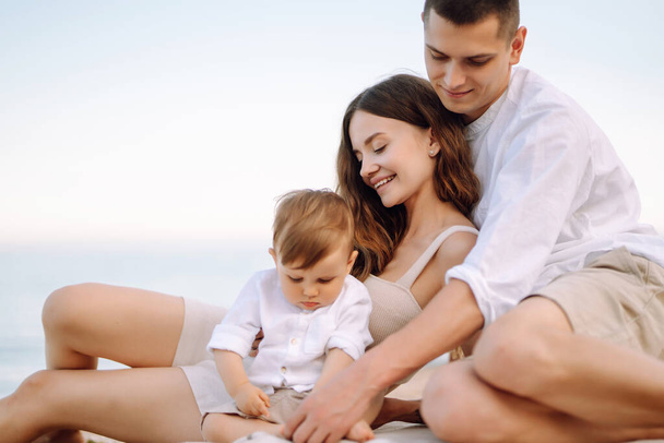 Young family on the beach. People are having fun on summer vacation. Father, mother and child against the background of the blue sea and sky. Travel, active lifestyle, vacation, rest concept. - Fotó, kép