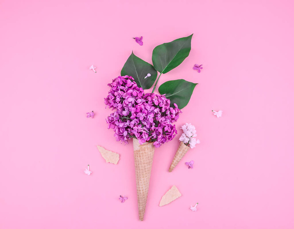 Lilac flowers in waffle cones lie in the middle on a pink background with space for text on the sides, top view close-up. - Foto, Imagem