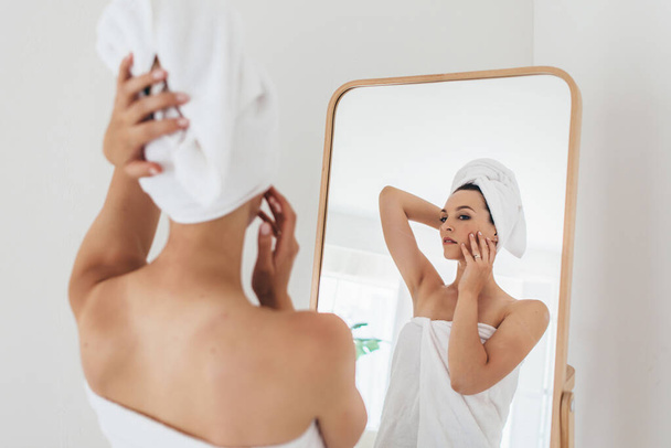 Femme se tient devant un miroir après un bain - Photo, image