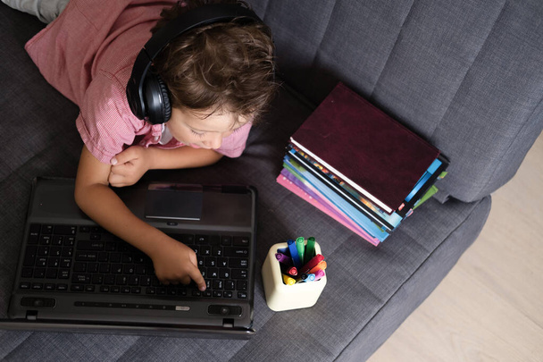 Cute caucasian boy using laptop and headphones studying at home - Foto, Bild