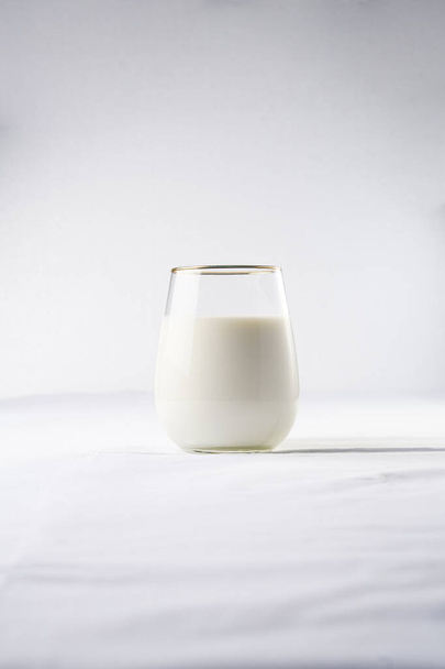 Ein Glas Milch auf der weißen Tischdecke - Foto, Bild