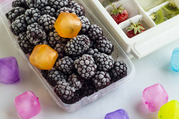 Fresh frozen of berries,kiwi and strawberries in ice tray,on white surface,top view - Valokuva, kuva