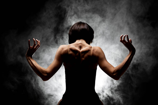 half silhouette modern ballet dancer posing on dark background with smoke - Foto, Imagem