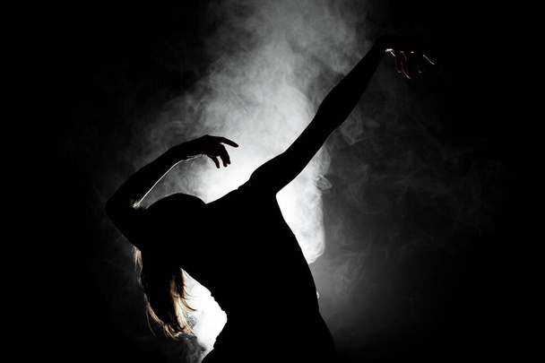 silhouette modern ballet dancer posing on dark background with smoke - Valokuva, kuva