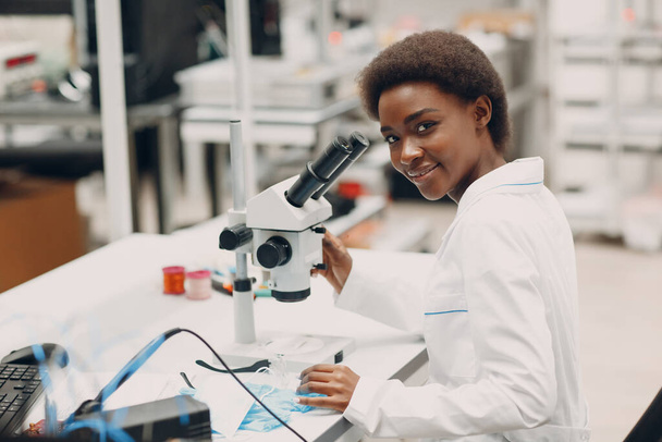 Επιστήμονας αφροαμερικανή γυναίκα που εργάζεται σε εργαστήριο με ηλεκτρονικά όργανα - Φωτογραφία, εικόνα
