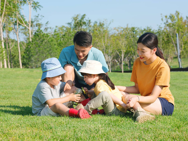 Szczęśliwa czteroosobowa rodzina bawiąca się w parku - Zdjęcie, obraz