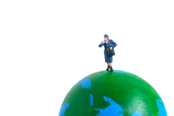 Miniature people toys conceptual photography. Global, international delivery service. Postman, courier standing above earth globe. - 写真・画像