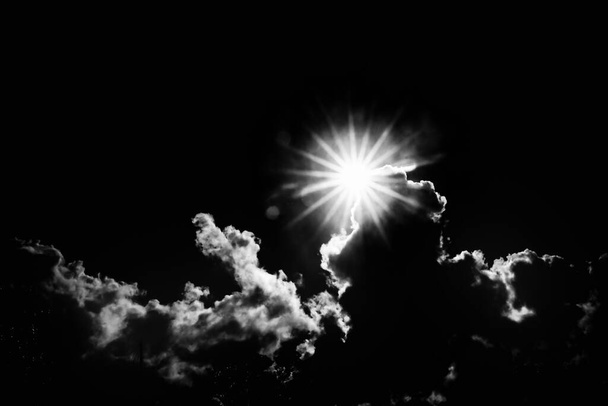 Sun bursts above cloud against blue sky in monochrome. - Photo, Image