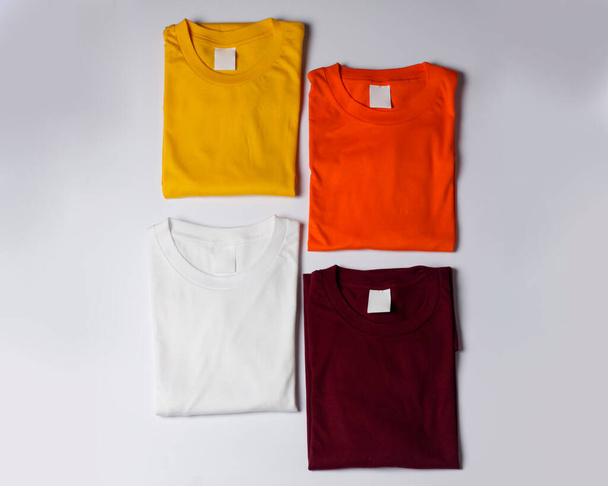 pile of colorful plain clothes. neatly arranged t-shirt mockup on a bright background. top view of a pile of neatly arranged clothes. Plain t-shirts from cotton fabric are ready to be displayed. - Zdjęcie, obraz