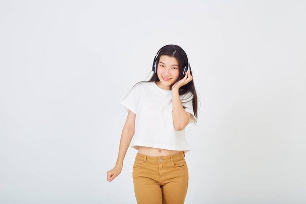 Молодая азиатка в наушниках и танцует на белом фоне - Фото, изображение