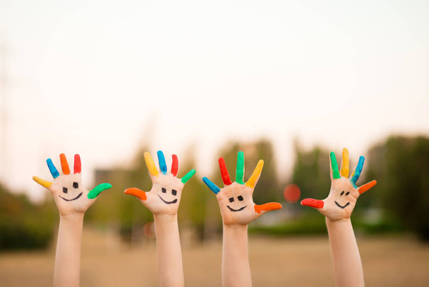 Niños manos en pintura colorida con la cara sonrisa divertida al aire libre - Foto, Imagen