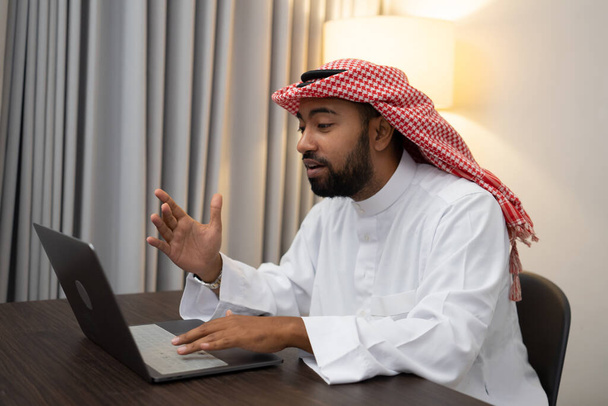an Arab businessman wearing a turban during a teleconference meeting using a laptop - Fotó, kép