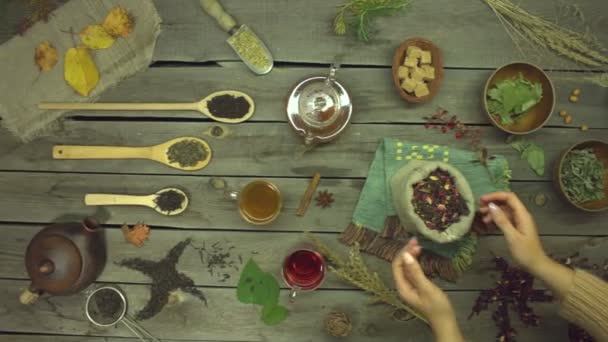 Red tea made from rose petals on an old wooden table. Flat lay. Still life with different types of tea: black, green, mate, hibiscus, floral, fruit, herbal.Female hands take a bag of hibiscus tea from the table. Slow motion 2x. - Footage, Video