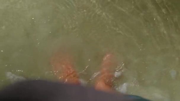 Ένας άντρας με τζιν περπατάει ξυπόλητος σε υγρή λάσπη καθώς το νερό υποχωρεί σε μια γαλήνια παραλία το καλοκαίρι. Η ακτή διαθέτει επίσης άργιλο καθαρότητας και φυσικές συνθήκες κατάλληλες για υπαίθριες δραστηριότητες και ταξίδια - Πλάνα, βίντεο