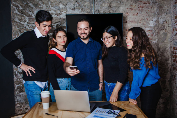 Молодая латиноамериканская бизнес-команда наслаждается свободным временем, просматривая видео на смартфоне в Мексике - Фото, изображение