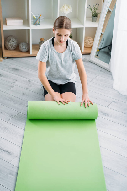 kids home sport athletic girl rolling up yoga mat - Fotoğraf, Görsel