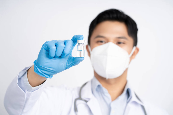Lekarz azjatycki trzymający szczepionkę lub lek w przezroczystym szkle na dłoni, szczepionkę przeciw grypie. Opieka zdrowotna i koncepcja medyczna. - Zdjęcie, obraz