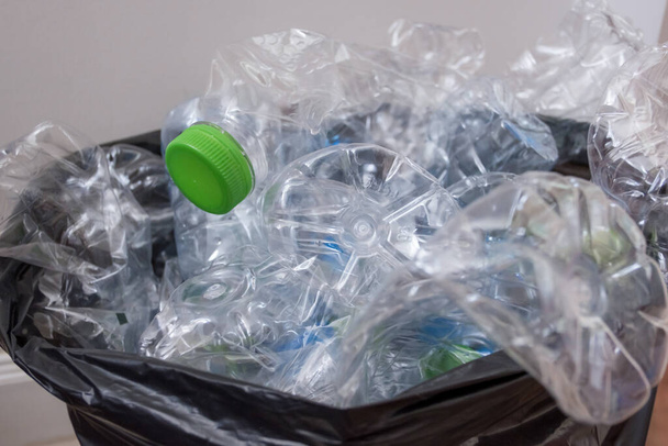 Műanyag palackok fekete szemeteszsákban, az újrahasznosításra várva. - Fotó, kép