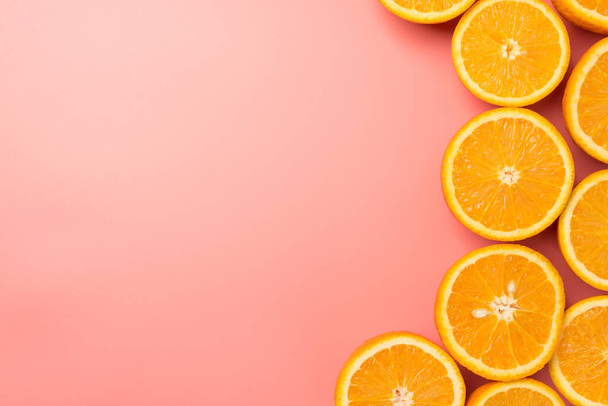 Top view kuva leikatut appelsiinit oikealla eristetty pastelli vaaleanpunainen tausta copyspace vasemmalla - Valokuva, kuva