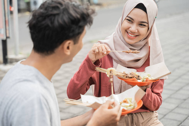couple enjoy eating chicken satay they bought from street food seller in indonesia - Valokuva, kuva