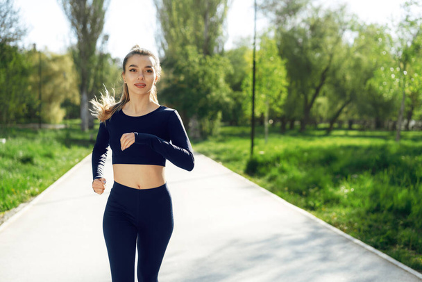 Sportlich fitte junge Frau joggt frühmorgens im Park - Foto, Bild