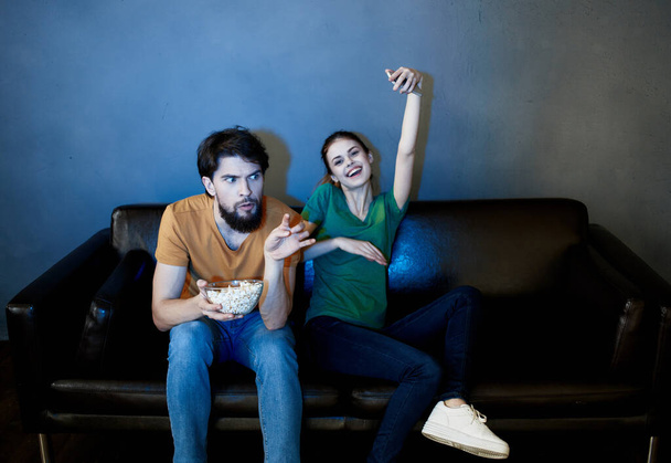 陽気な夫婦がソファでテレビのエンターテイメントを見て - 写真・画像