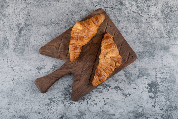 Fresh and tasty croissants placed on a wooden cutting board . High quality photo - Zdjęcie, obraz
