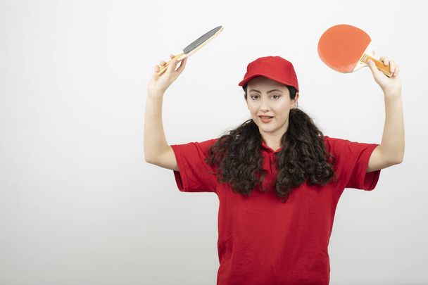 卓球ラケットで遊ぶ赤い制服を着たブルネットの女性。高品質の写真 - 写真・画像
