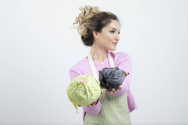 Молодая женщина в фартуке с капустой пропагандирует здоровый образ жизни. Высокое качество фото - Фото, изображение