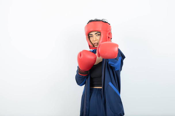 Foto de boxeadora femenina en forma con guantes rojos y casco mostrando sus golpes. Foto de alta calidad - Foto, Imagen