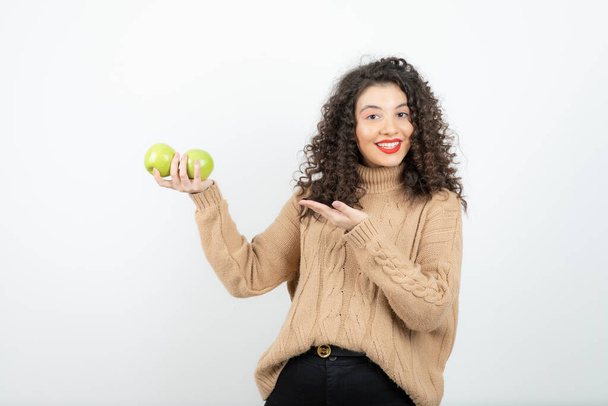 Image of curly woman with red lipstick with green apples standing. High quality photo - Valokuva, kuva
