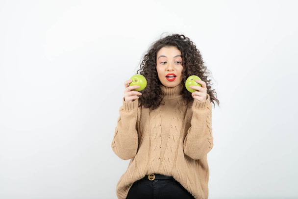 Afbeelding van krullende vrouw met rode lippenstift met staande groene appels. Hoge kwaliteit foto - Foto, afbeelding