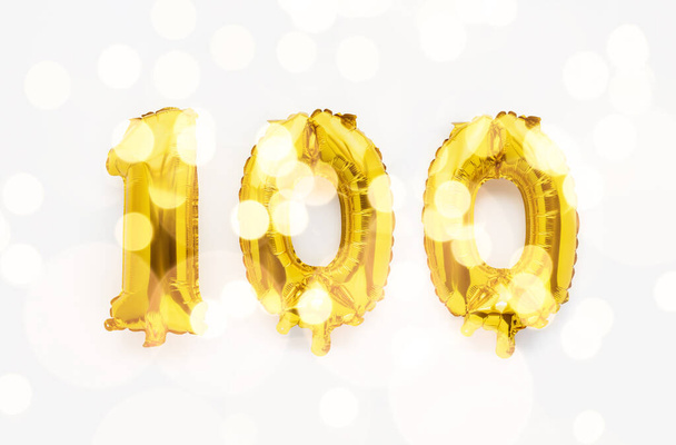Νούμερο 100 εκατό χρυσό αλουμινόχαρτο διακόσμηση κόμμα μπαλόνι σε λευκό φόντο, επέτειο γενεθλίων - Φωτογραφία, εικόνα