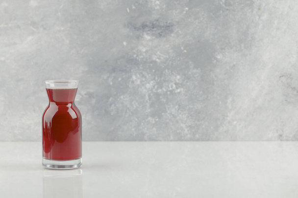Un vaso de jugo de granada fresco colocado sobre una mesa blanca. Foto de alta calidad - Foto, imagen