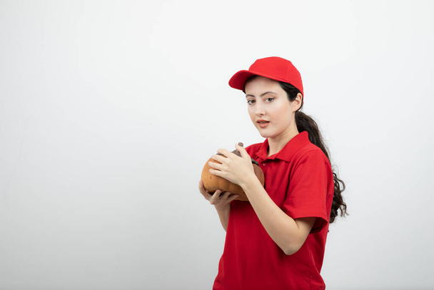 Picture of brunette woman in red uniform holding pumpkin . High quality photo - Photo, Image
