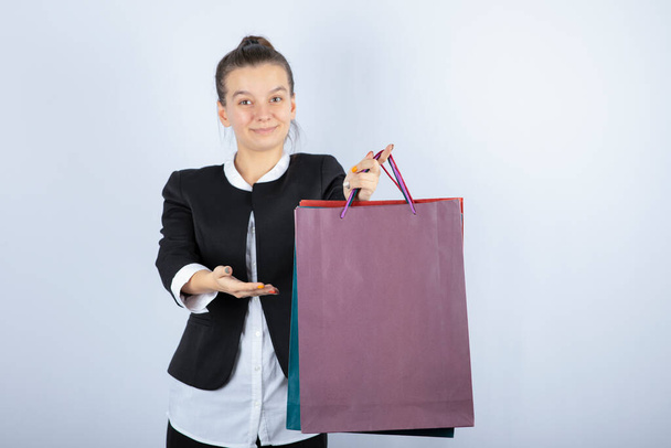 Imagen de una mujer joven sosteniendo bolsas de compras sobre fondo blanco. Foto de alta calidad - Foto, Imagen