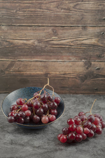 Deep plate of red ripe grapes on marble table. High quality photo - 写真・画像