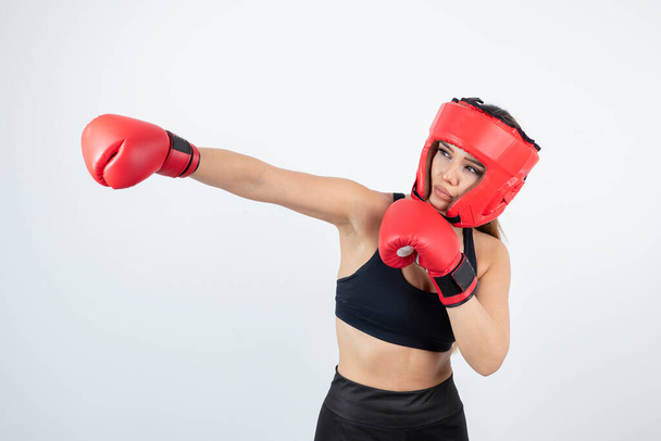 Portré fiatal női bokszoló piros kesztyűben és sisak képzés. Kiváló minőségű fénykép - Fotó, kép