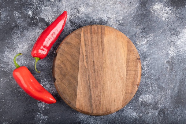 Červené chilli papričky s dřevěnou řezací deskou na mramoru. Kvalitní fotografie - Fotografie, Obrázek