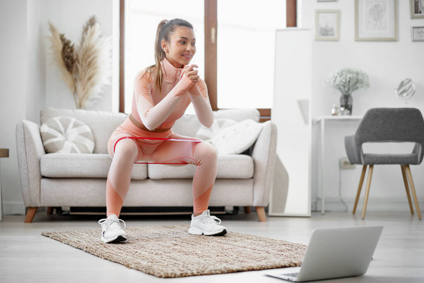 Young fitness girl doing sport exercises at her living room at home - Photo, image