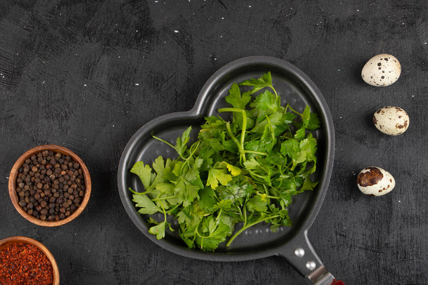 Pan of parsley leaves, condiments and quail eggs on black surface. High quality photo - Photo, Image