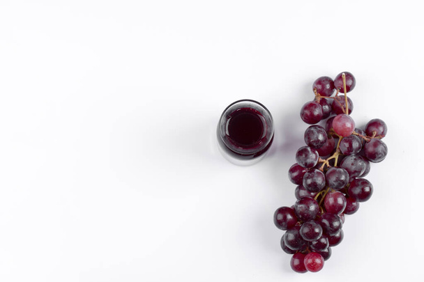 Bunch of grapes with a glass pitcher of juice placed on a white table. High quality photo - Foto, afbeelding