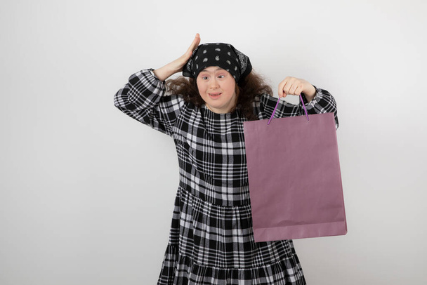 Urocza młoda dziewczyna z zespołem Downa trzymająca torbę na zakupy. Wysokiej jakości zdjęcie - Zdjęcie, obraz