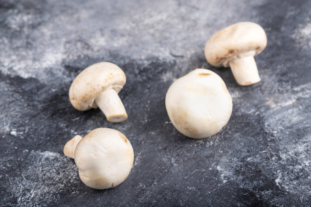 Сырые спелые шампиньонские грибы, помещенные на мраморный стол. Высокое качество фото - Фото, изображение