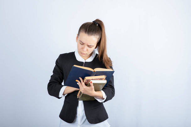 Portret van een jong meisje dat een interessant boek leest over witte achtergrond. Hoge kwaliteit foto - Foto, afbeelding