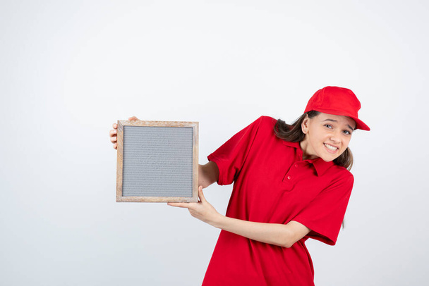 Obrázek mladé dívky v červené uniformě stojící a držící rám. Kvalitní fotografie - Fotografie, Obrázek