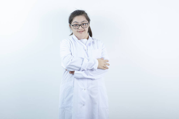 Chica joven con uniforme de médico de pie con los brazos cruzados. Foto de alta calidad - Foto, imagen